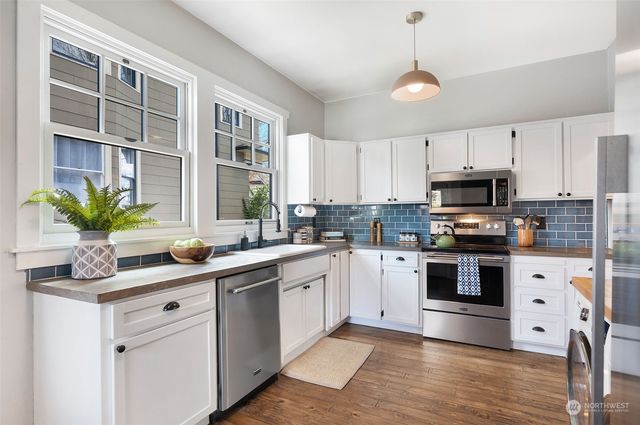 a kitchen with stainless steel appliances granite countertop a sink a stove and cabinets