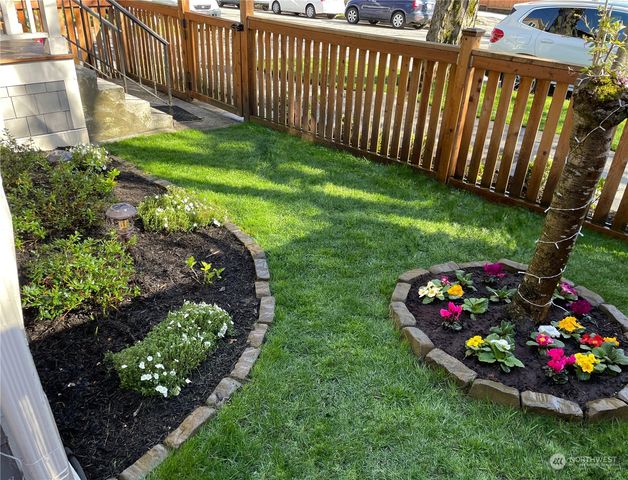 a view of a garden with flowers and wooden fence