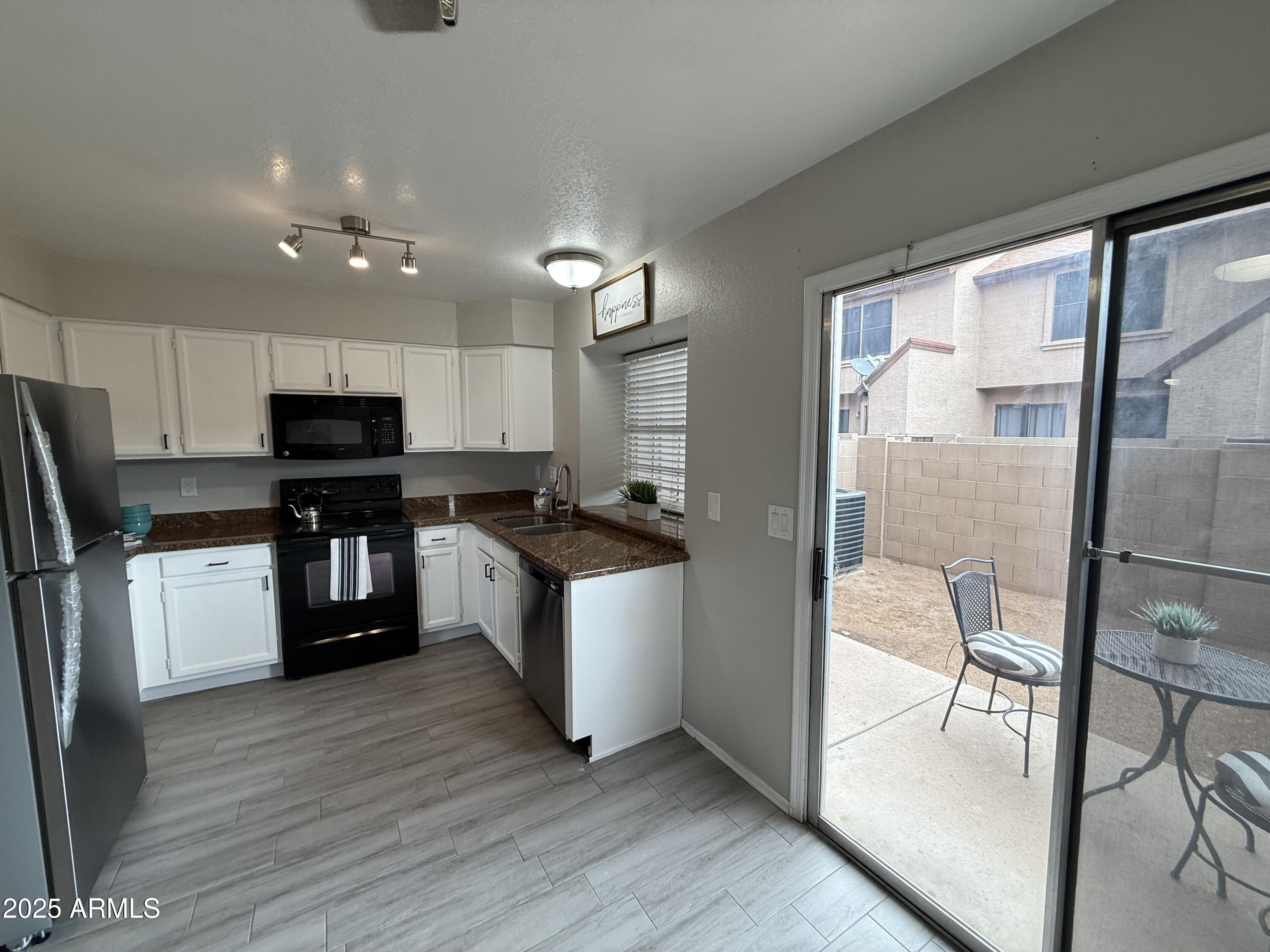 7977 West Wacker Road, Unit 249 Peoria, AZ 85381 - Photo 1 of 17 a kitchen with granite countertop a refrigerator a sink a stove top oven a kitchen island and chairs with wooden floor