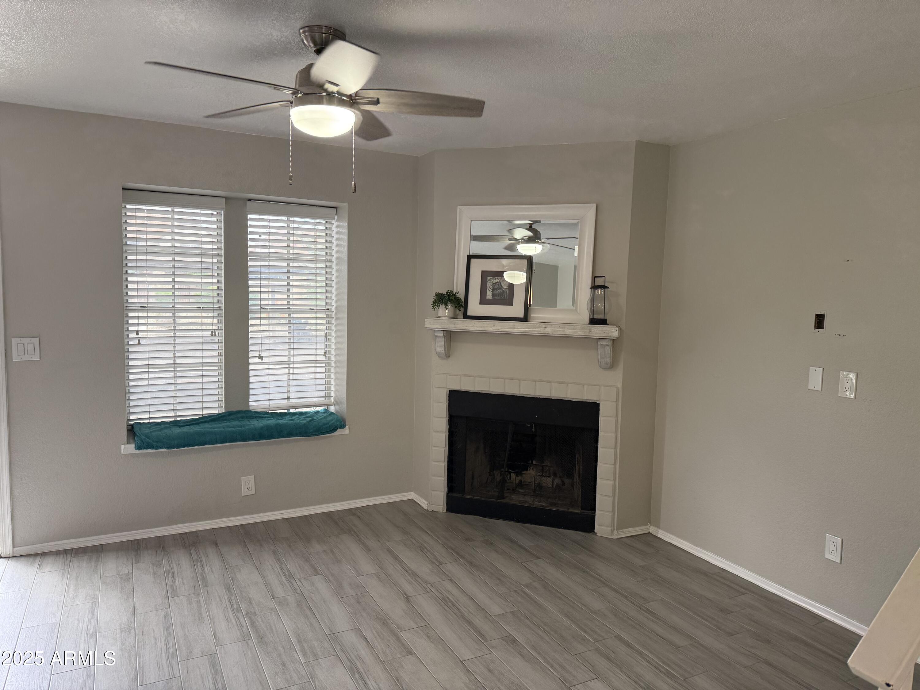 7977 West Wacker Road, Unit 249 Peoria, AZ 85381 - Photo 9 of 17 a view of an empty room with wooden floor fireplace and a window