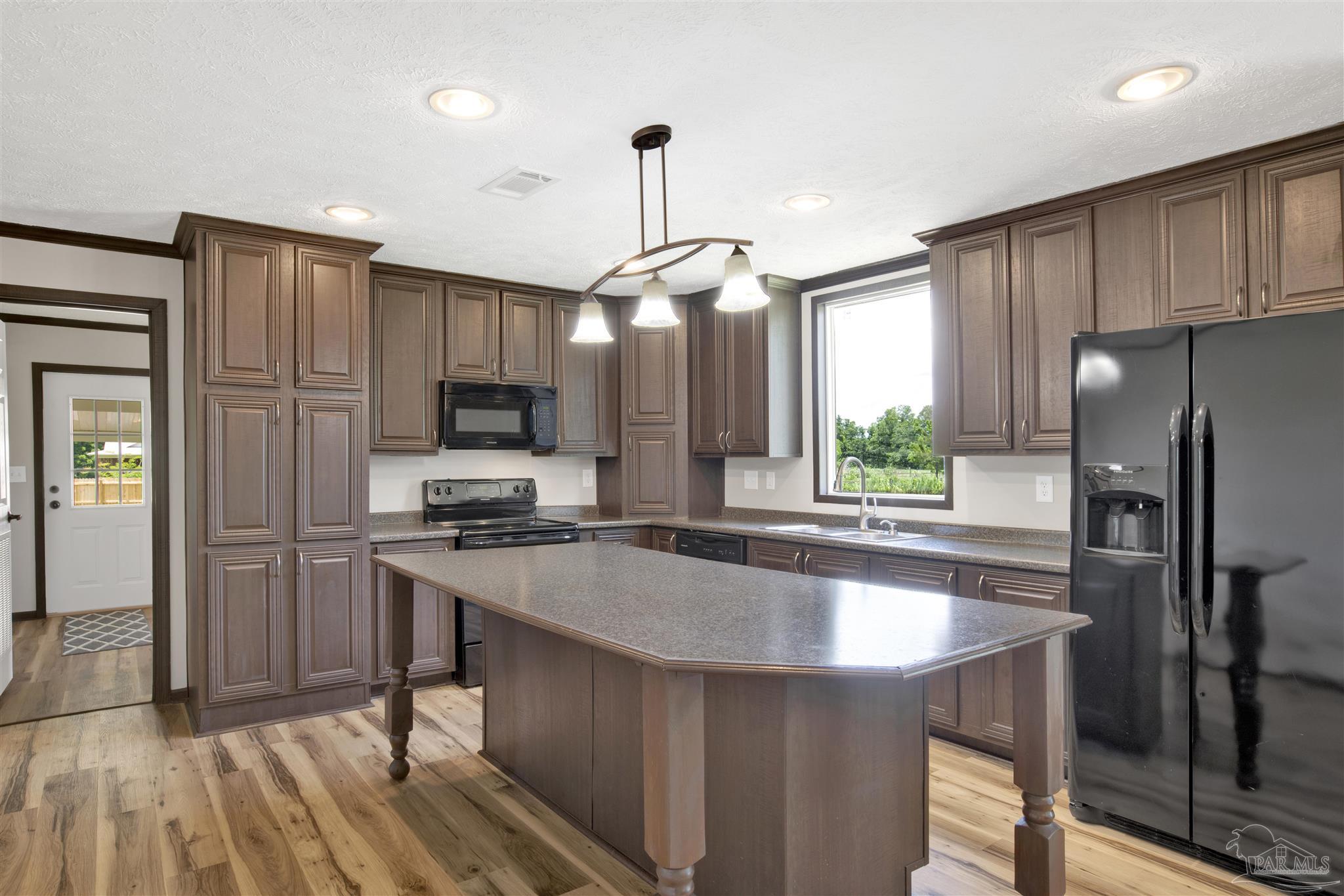 6594 Will Jones Road Jay, FL 32565 - Photo 11 of 39 a kitchen with stainless steel appliances granite countertop a refrigerator a sink dishwasher a stove and white countertops with wooden floor