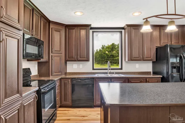 a kitchen with stainless steel appliances granite countertop a refrigerator a sink a stove a microwave and wooden cabinets