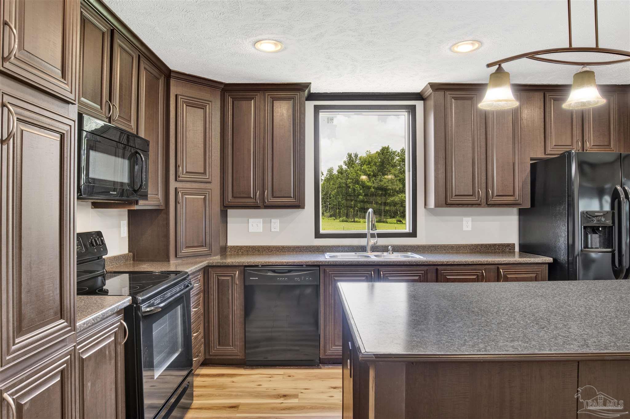 6594 Will Jones Road Jay, FL 32565 - Photo 12 of 39 a kitchen with stainless steel appliances granite countertop a refrigerator a sink a stove a microwave and wooden cabinets