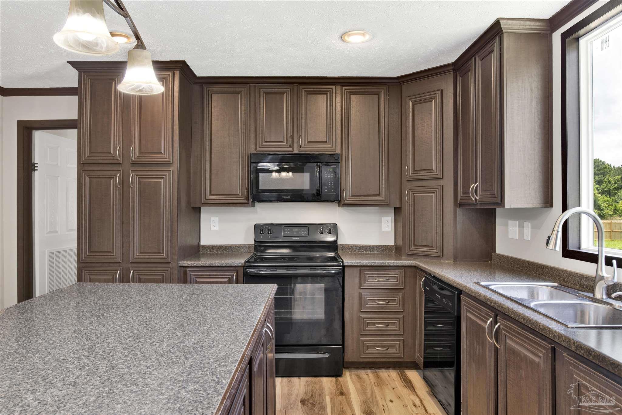 6594 Will Jones Road Jay, FL 32565 - Photo 13 of 39 a kitchen with kitchen island granite countertop a stove sink and cabinets