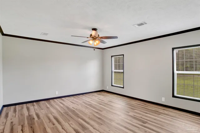 an empty room with wooden floor chandelier fan and windows