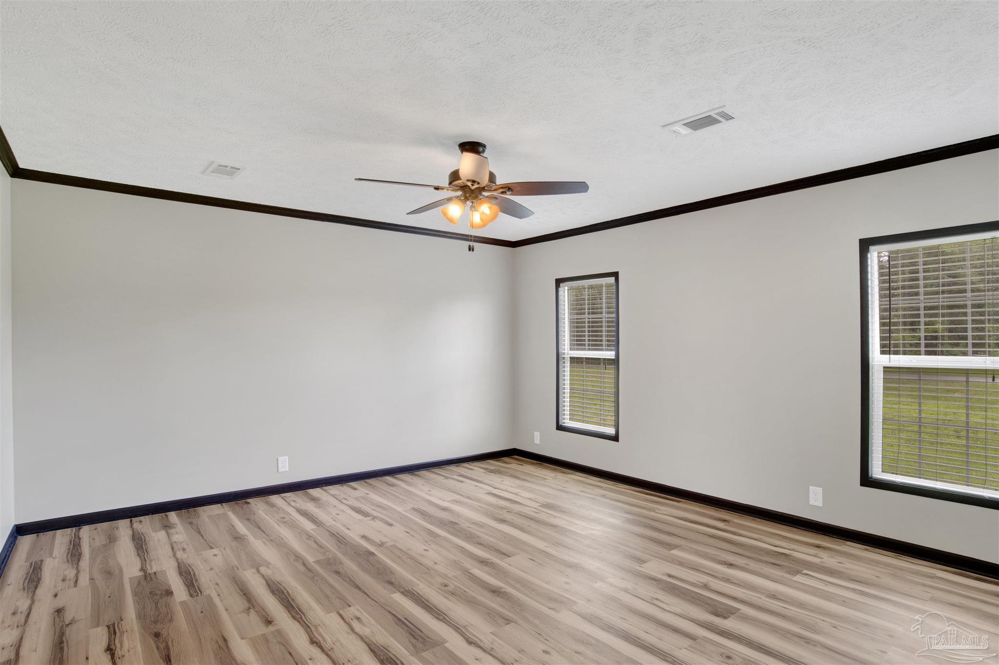 6594 Will Jones Road Jay, FL 32565 - Photo 17 of 39 an empty room with wooden floor chandelier fan and windows
