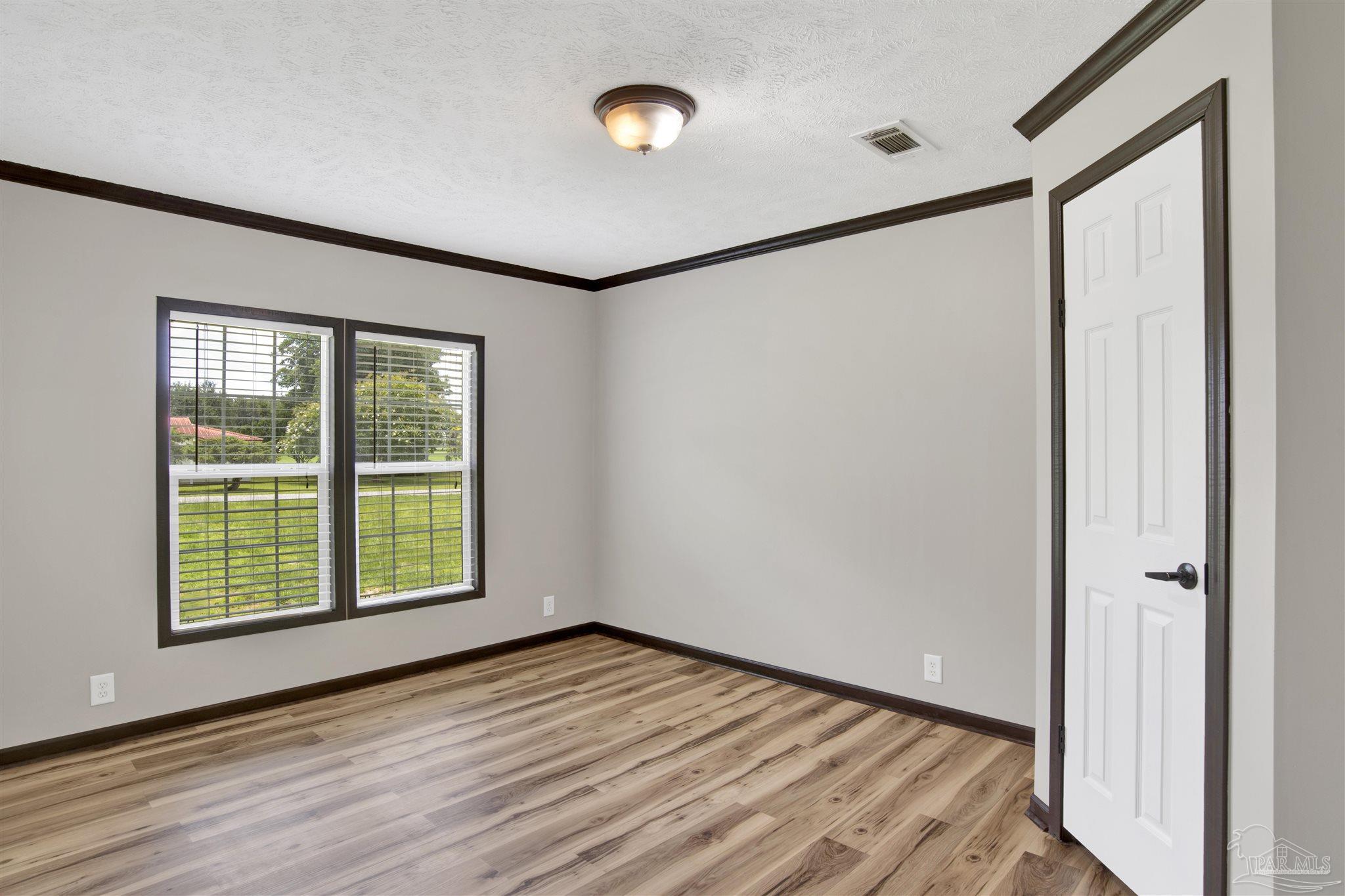 6594 Will Jones Road Jay, FL 32565 - Photo 24 of 39 a view of an empty room with wooden floor and a window