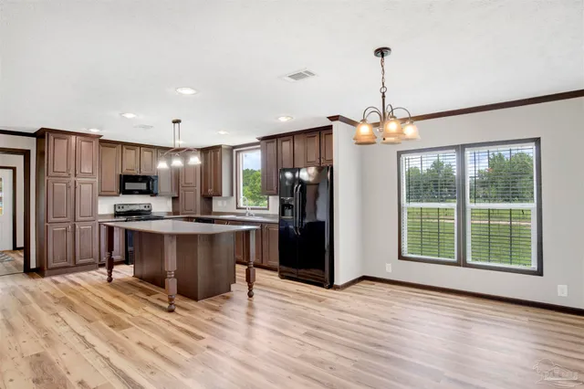 a kitchen with stainless steel appliances granite countertop a refrigerator a stove a sink dishwasher and a refrigerator with wooden floor