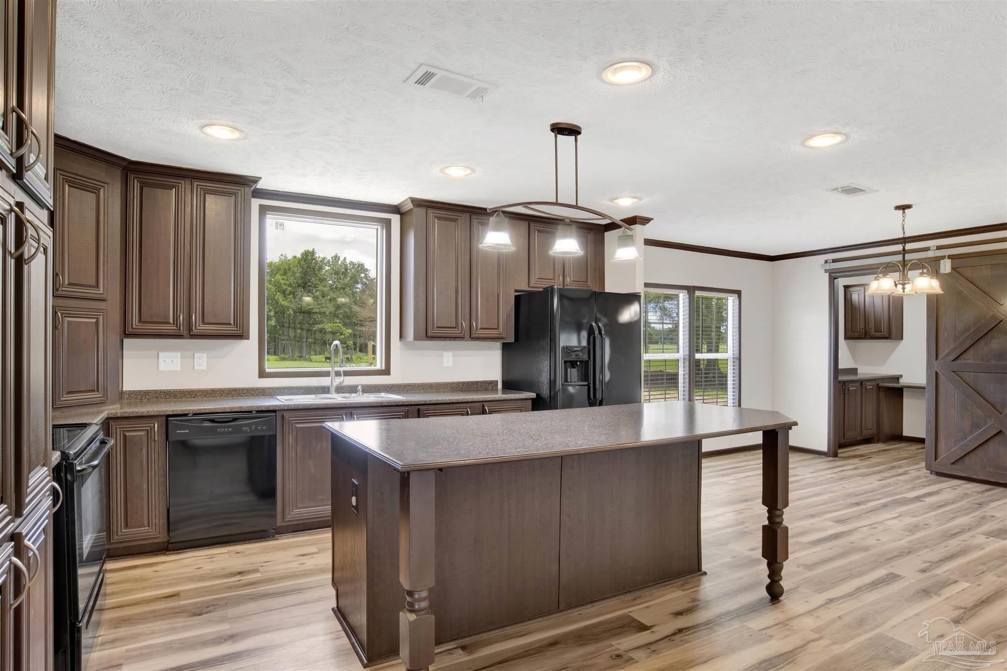 6594 Will Jones Road Jay, FL 32565 - Photo 10 of 39 a large kitchen with a center island wooden floor stainless steel appliances and cabinets