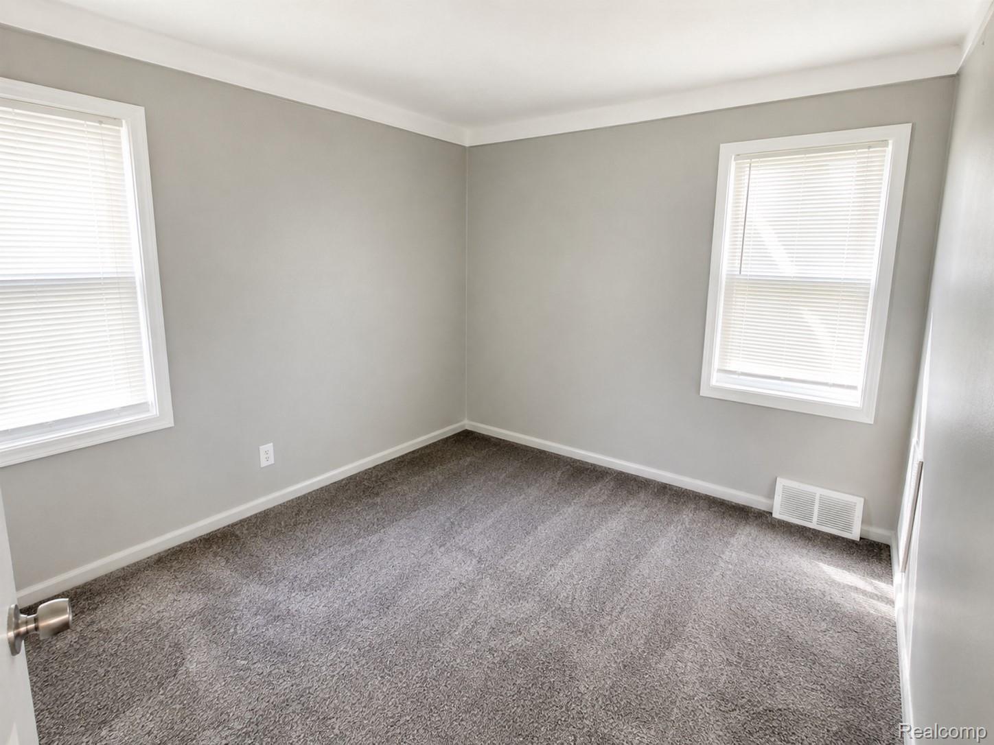 13590 Rutherford Street Detroit, MI 48227 - Photo 6 of 10 Bright corner bedroom with dual windows providing natural light, neutral wall finishes, and plush carpet flooring