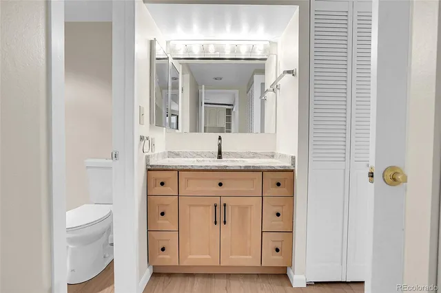 a bathroom with a granite countertop sink a toilet and a mirror
