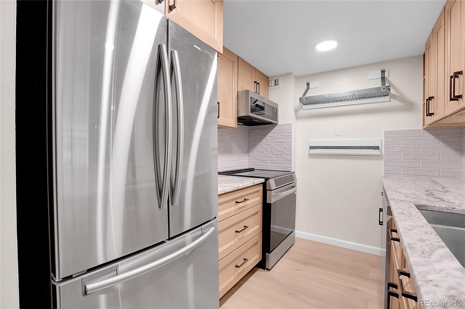 1777 Larimer Street, Unit 807 Denver, CO 80202 - Photo 9 of 25 a kitchen with white cabinets and stainless steel appliances