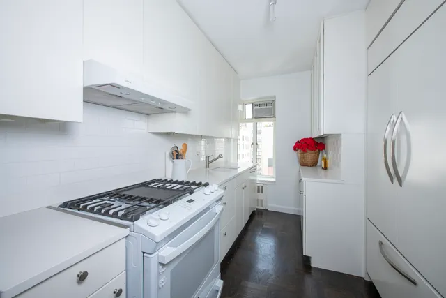 a kitchen that has a lot of white cabinets and wooden floor