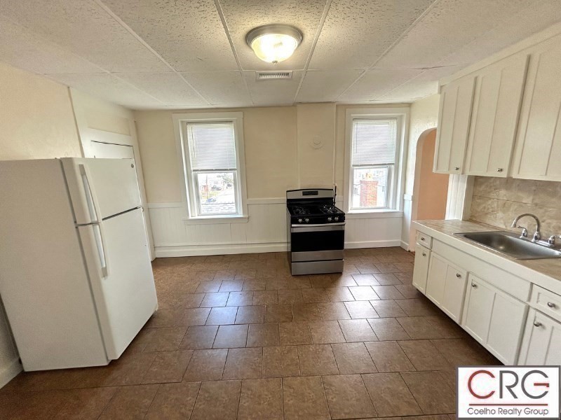 31 Elmwood Street, Unit 6 Revere, MA 02151 - Photo 13 of 16 a kitchen with granite countertop a refrigerator and a stove top oven