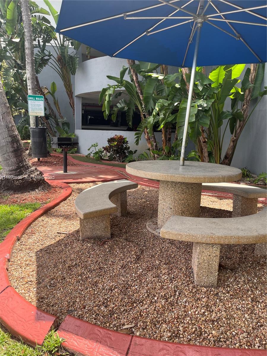 5099 Northwest 7th Street, Unit 1005 Miami, FL 33126 - Photo 13 of 35 a view of a backyard with table and chairs under an umbrella