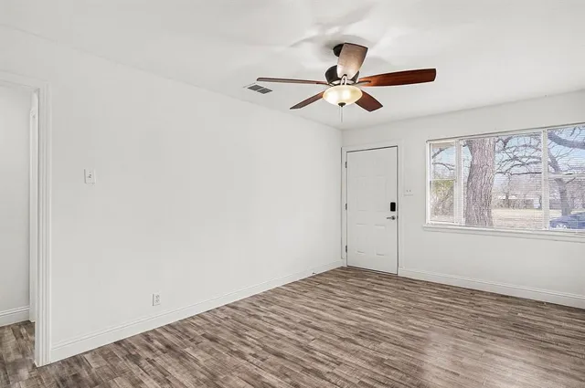 a view of empty room with wooden floor and fan