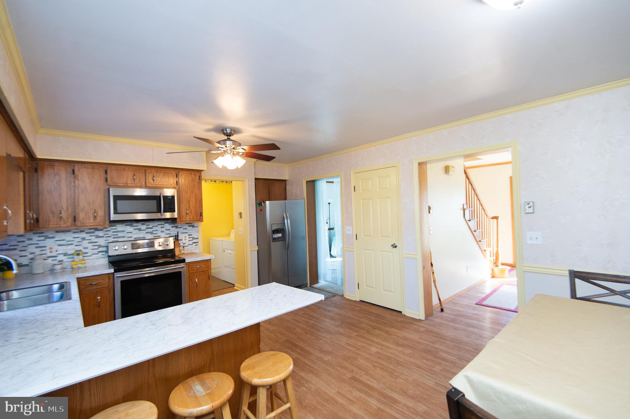807 Bayly Road Cambridge, MD 21613 - Photo 7 of 36 a kitchen with stainless steel appliances kitchen island granite countertop a refrigerator a stove top oven and a dining table with wooden floor