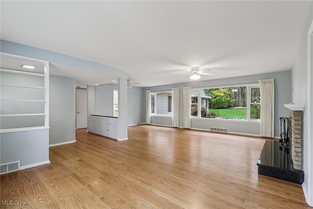 33300 South Woodland Road Cleveland, OH 44124 - Photo 11 of 50 Unfurnished living room with light wood-style flooring, a fireplace, and a ceiling fan