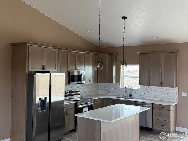 a kitchen with stainless steel appliances granite countertop a sink a stove a refrigerator and island
