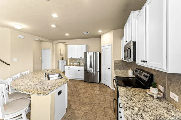 a kitchen with stainless steel appliances granite countertop a sink refrigerator and cabinets
