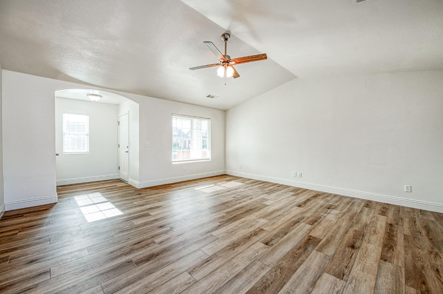 5176 West Michigan Avenue Fresno, CA 93722 - Photo 23 of 37 an empty room with wooden floor ceiling fan and windows