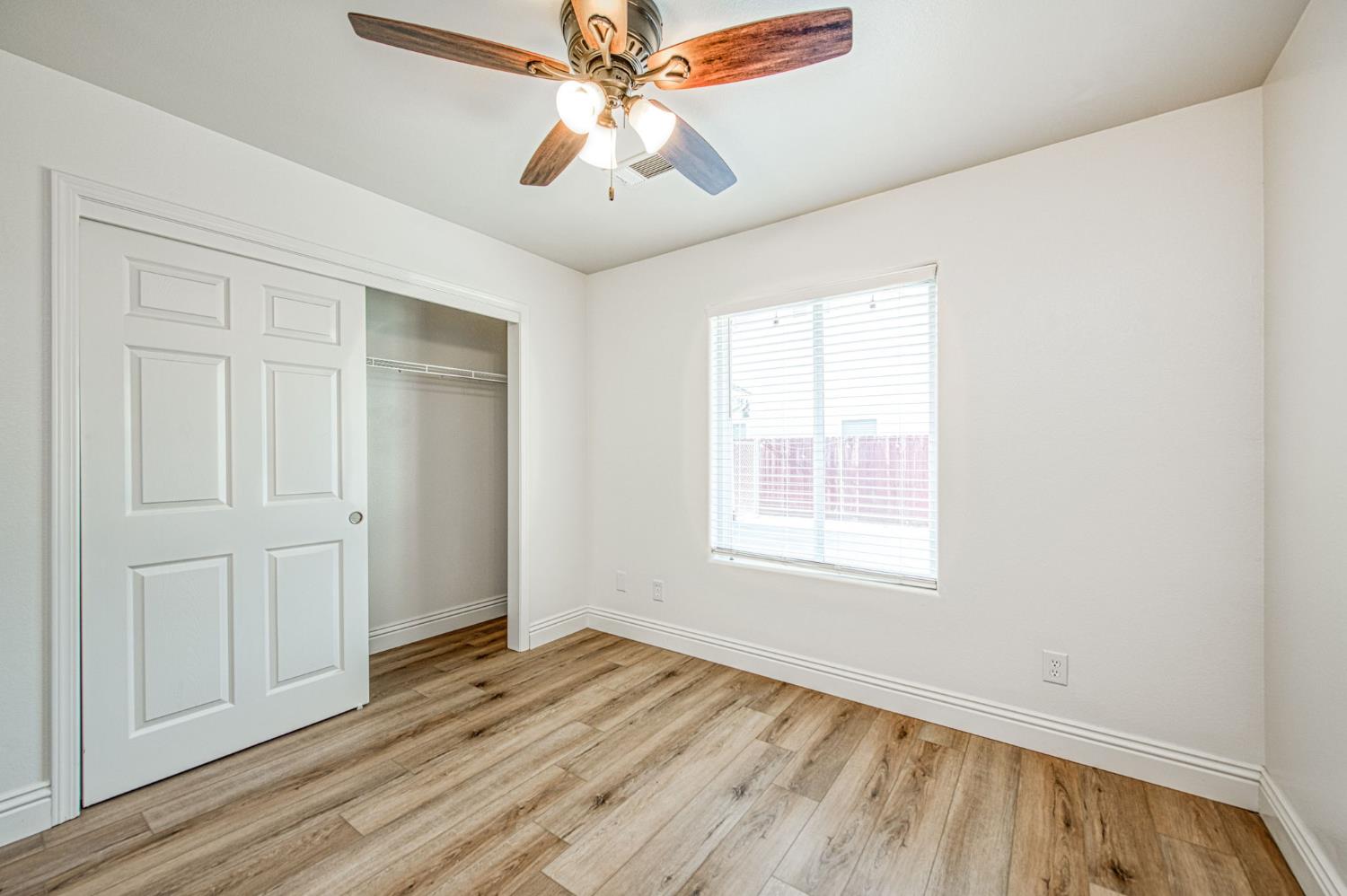 5176 West Michigan Avenue Fresno, CA 93722 - Photo 34 of 37 an empty room with wooden floor chandelier fan and windows