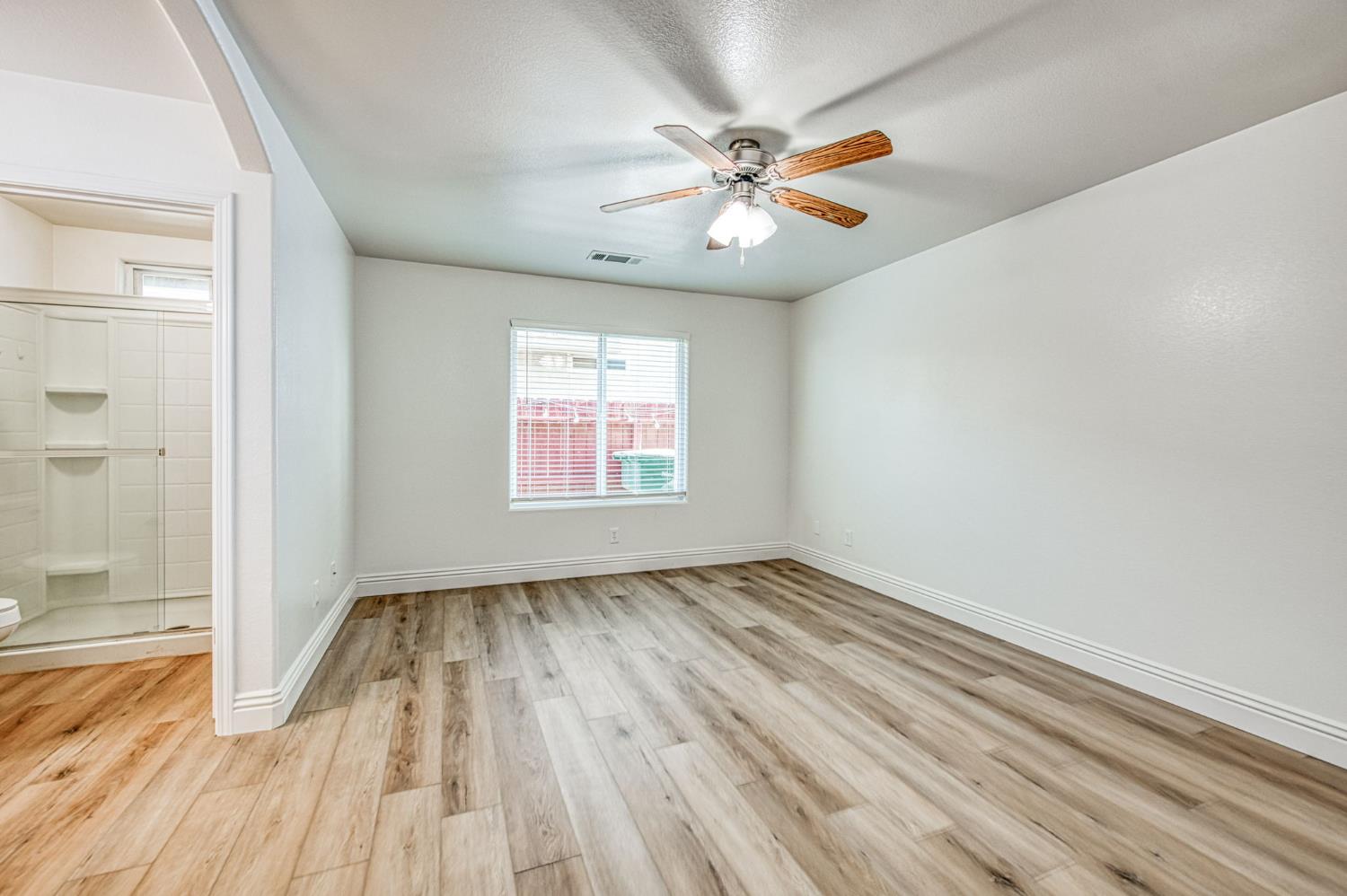 5176 West Michigan Avenue Fresno, CA 93722 - Photo 9 of 37 an empty room with wooden floor fan and windows