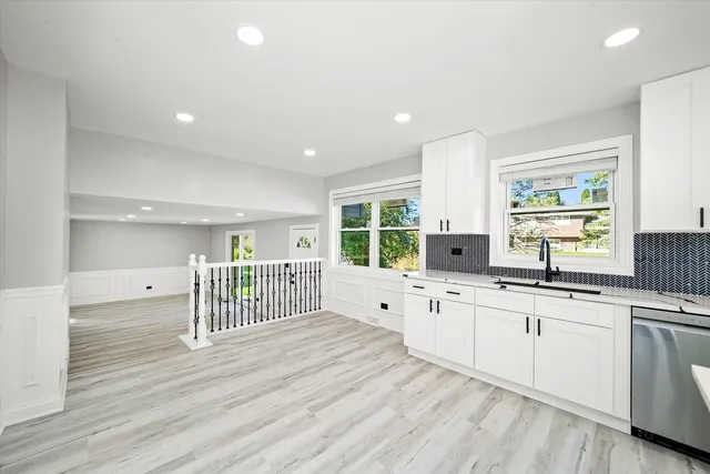 a open kitchen with kitchen island white cabinets and wooden floor