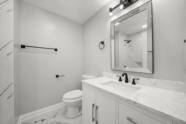 a bathroom with a granite countertop sink a toilet and a mirror