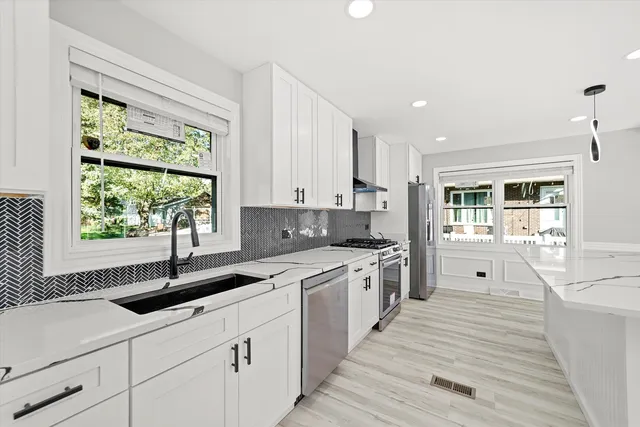 a kitchen with stainless steel appliances granite countertop a sink a stove and a window
