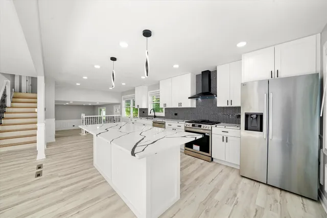 a large kitchen with stainless steel appliances kitchen island granite countertop a stove a refrigerator a oven and a sink with large countertops