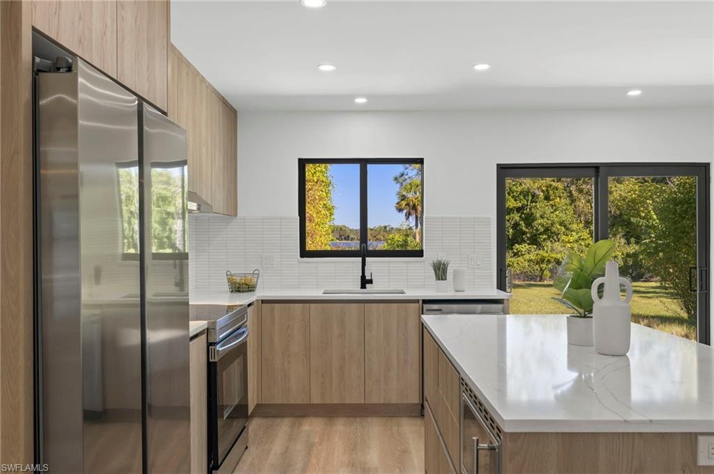 3613 Poplar Way Naples, FL 34112 - Photo 11 of 43 a kitchen with stainless steel appliances granite countertop a sink a stove and a refrigerator