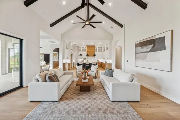 a large kitchen with stainless steel appliances a sink dishwasher a stove a dining table and chairs with wooden floor