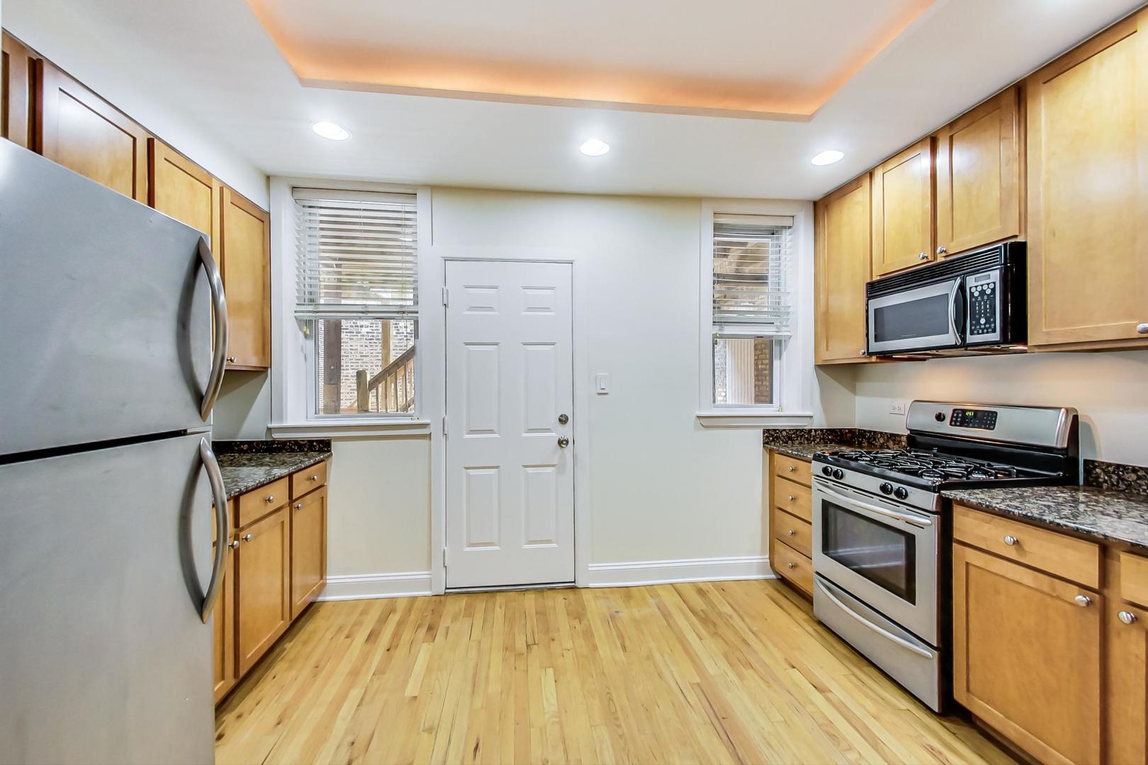 4109 North Sheridan Road, Unit 2S Chicago, IL 60613 - Photo 7 of 17 a kitchen with stainless steel appliances granite countertop a stove top oven a refrigerator and a microwave