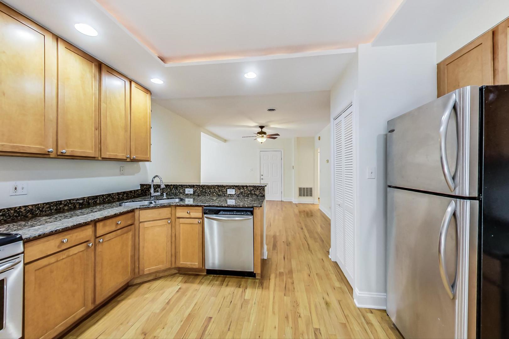 4109 North Sheridan Road, Unit 2S Chicago, IL 60613 - Photo 9 of 17 a kitchen with granite countertop stainless steel appliances a refrigerator a sink and cabinets