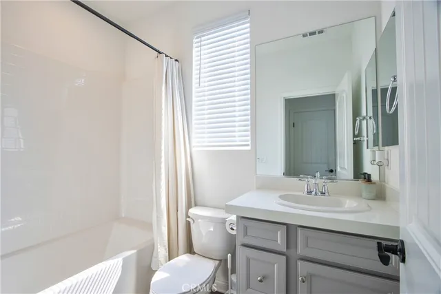 an empty room with a ceiling fan and kitchen view