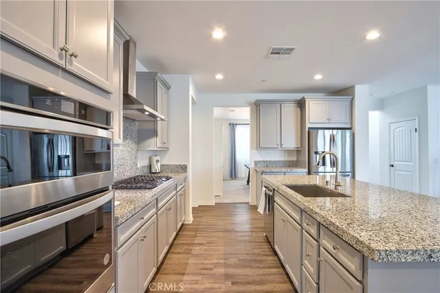 a large kitchen with stainless steel appliances kitchen island a refrigerator and a stove top oven