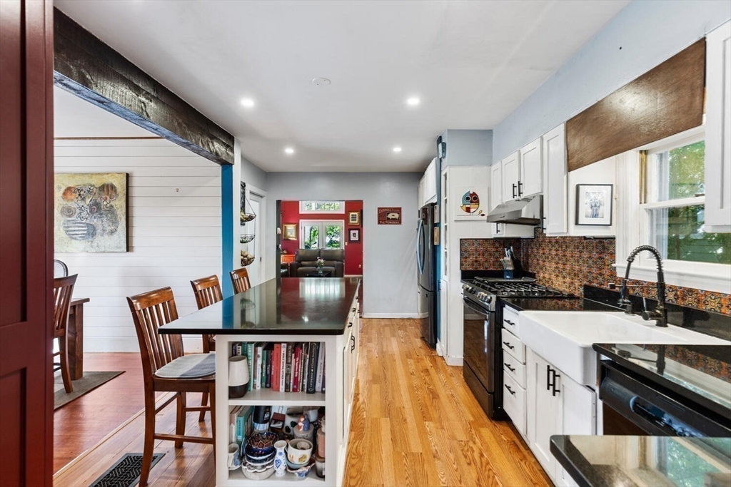 28 Gordon Road Medford, MA 02155 - Photo 5 of 41 a kitchen with stainless steel appliances granite countertop a stove top oven a sink a dining table and chairs with wooden floor