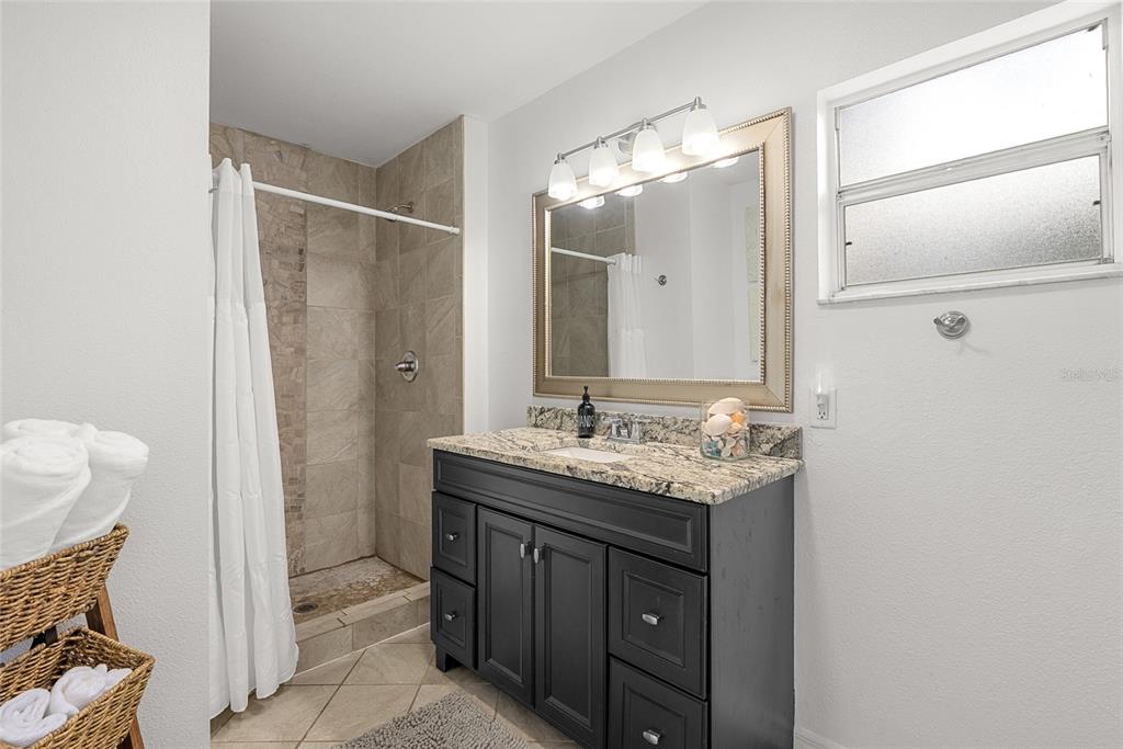 4939 100th Way North St. Petersburg, FL 33708 - Photo 19 of 43 a bathroom with a granite countertop sink a mirror and a shower