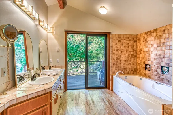 a spacious bathroom with a tub sink and mirror