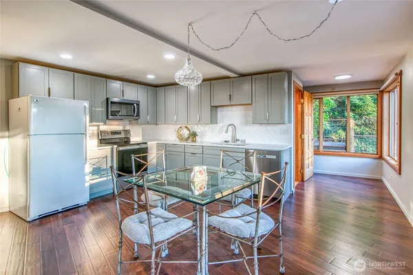 a kitchen with stainless steel appliances a dining table chairs refrigerator and sink