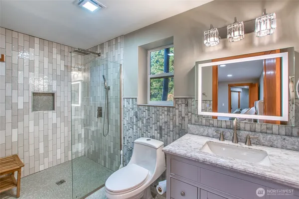 a bathroom with a granite countertop sink toilet a mirror a vanity and shower