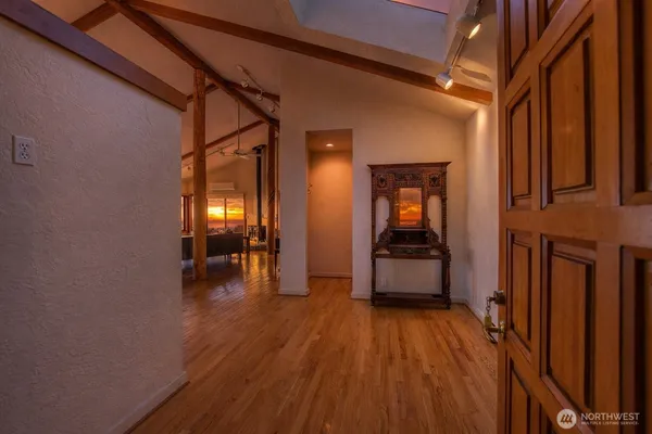 a view of a hallway with wooden floor and a dining room