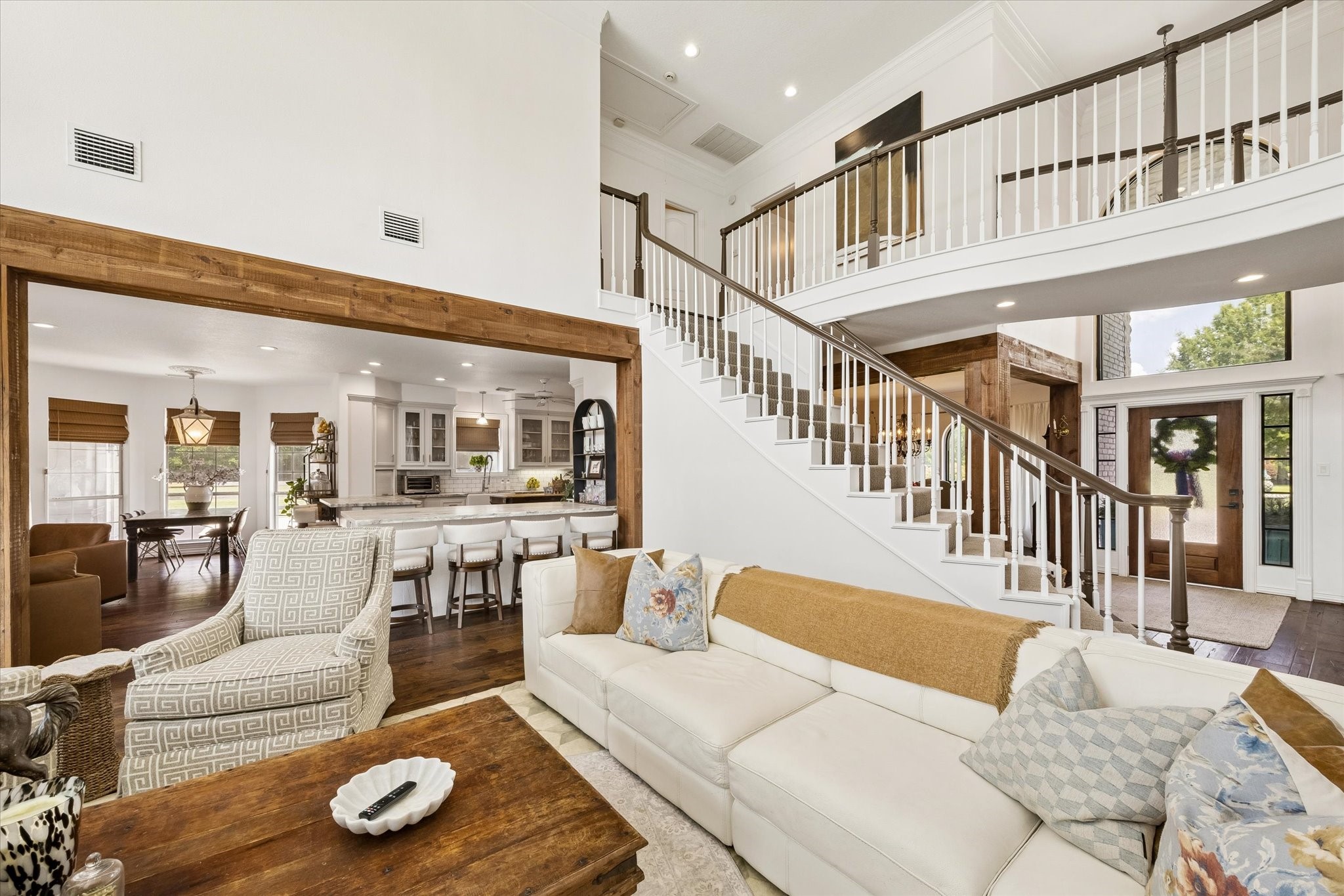 6819 Still Meadow Street Spring, TX 77389 - Photo 16 of 50 Spacious living area with high ceilings and an elegant staircase, seamlessly connected to a modern kitchen and dining space, creating a warm and inviting atmosphere.