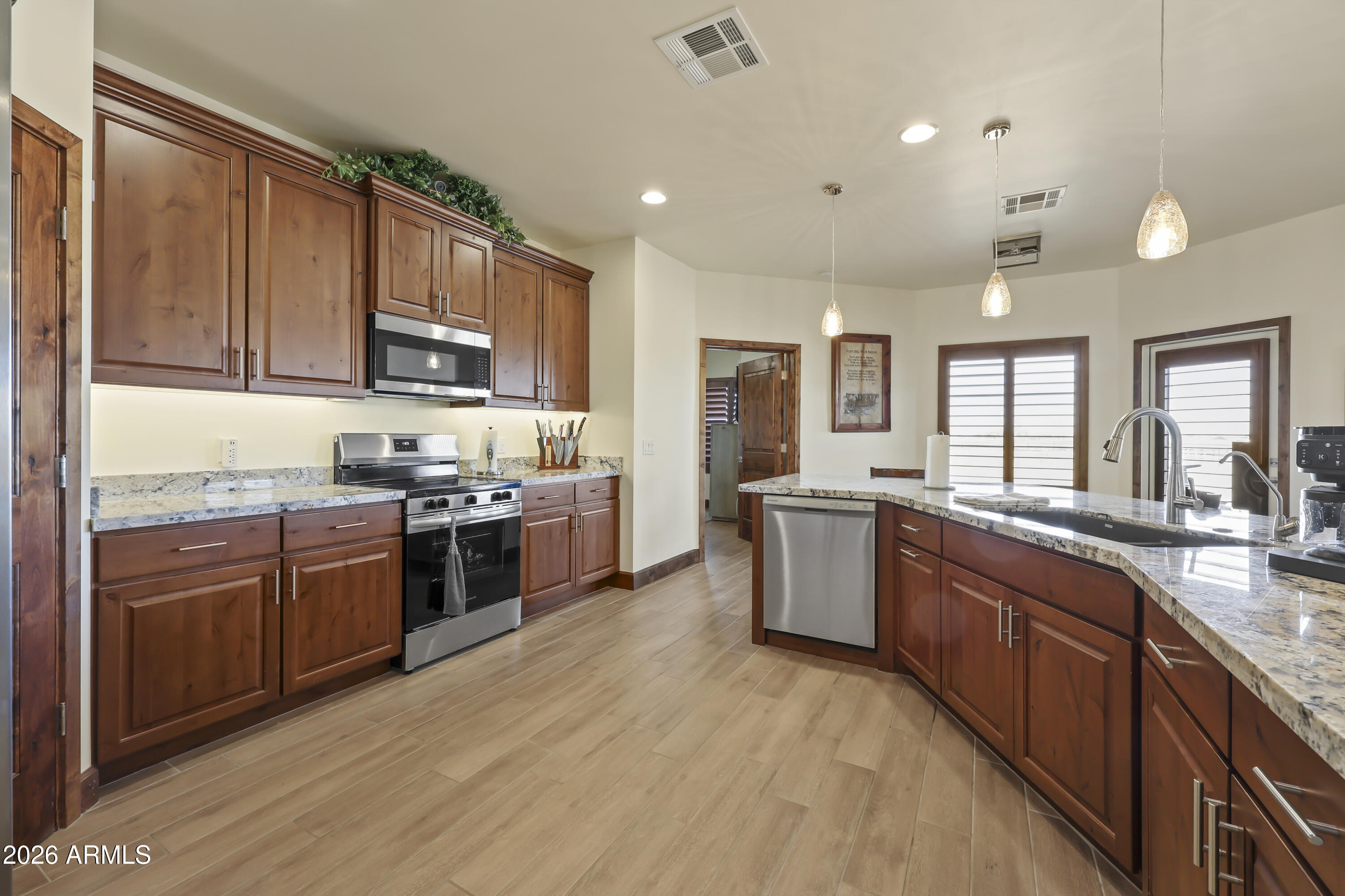 49370 West Val Vista Road Maricopa, AZ 85139 - Photo 5 of 58 a large kitchen with stainless steel appliances granite countertop a large stove top oven a sink dishwasher a dining table and chairs with wooden floor