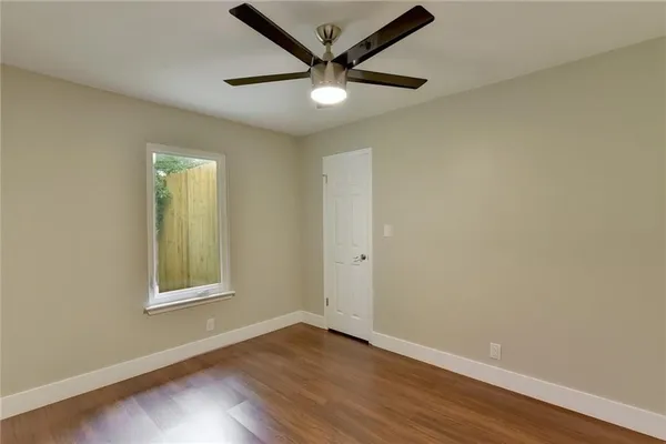 an empty room with wooden floor ceiling fan and windows