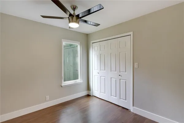 an empty room with wooden floor ceiling fan and windows