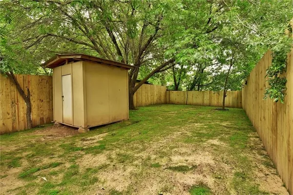 a view of a backyard with large tree and wooden fence
