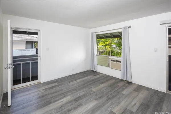 an empty room with wooden floor windows and entrance