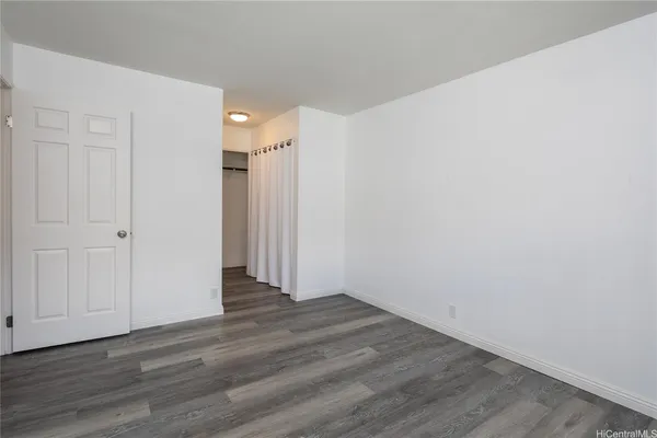 a view of an empty room with wooden floor and closet